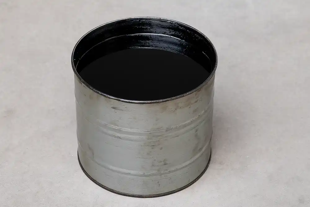 نمایی از یک حلب فلزی قدیمی که داخل آن با قیر داغ و سیاه پر شده